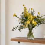 זר Wildflower צהוב וכחול על מדף עץ צר בדירה תל אביבית קטנה
